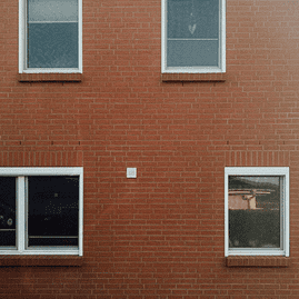 Hausfassade aus Backsteinen mit vier Fenstern