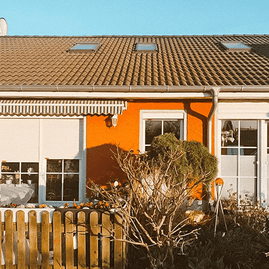 Haus mit orangefarbener Fassade und Fensterwand