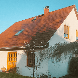 helles Haus mit rotem Steildach