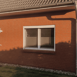 Haus mit Backsteinfassade mit Regenrinne und Fenster mit weißem Rahmen