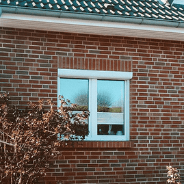 Backsteinfassade eines Hauses mit Fenster mit weißen Rahmen